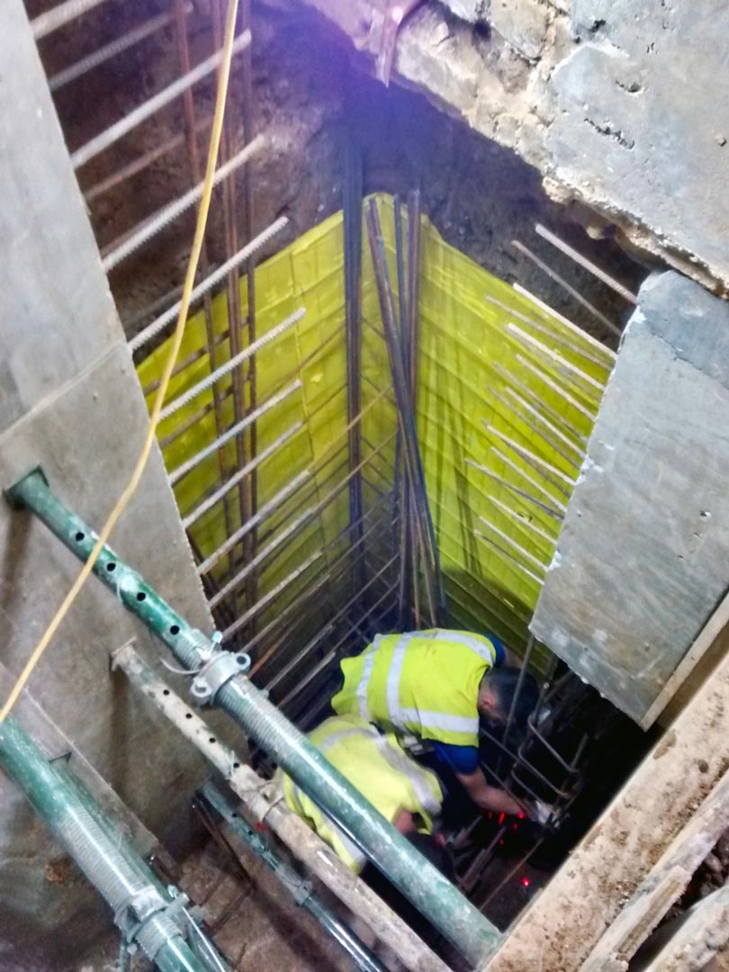 Steel fixers working below ground positioning and securing steel reinforcing bars and mesh to underpin a Victorian house with reinforced concrete