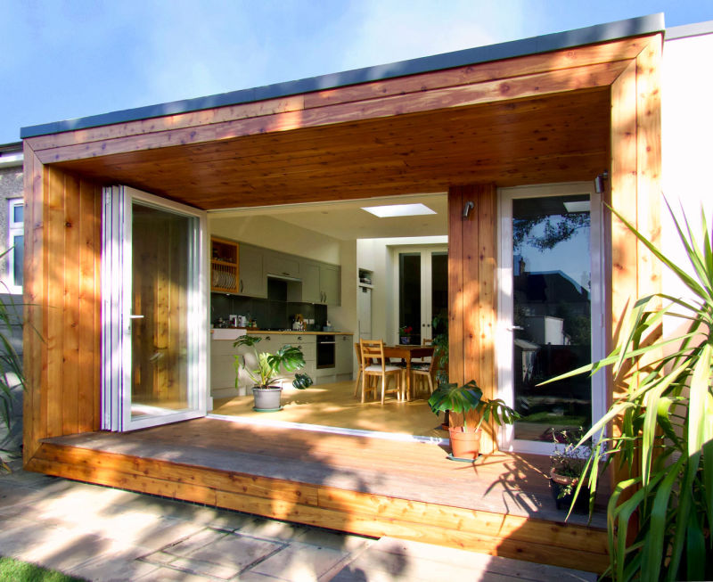 sun shining into modern kitchen extension with bifold doors and timber canopy structure