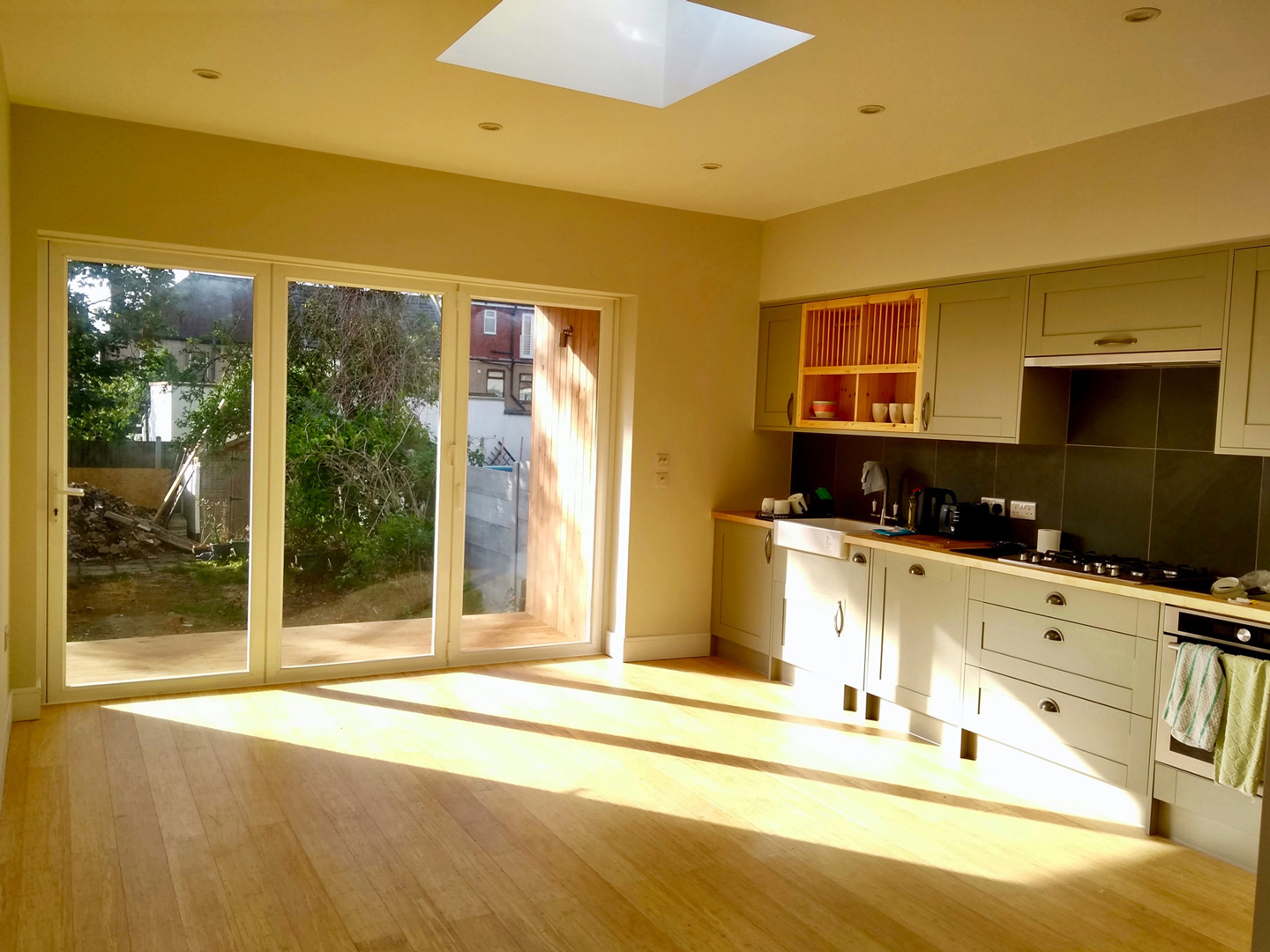 sun shining into modern kitchen extension through bifold doors