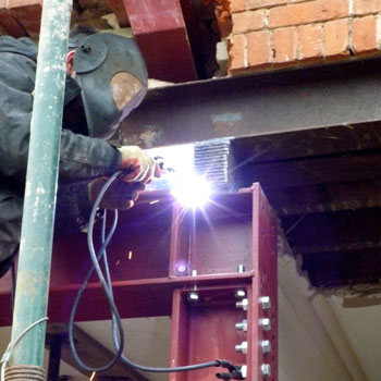 welder welding structural steel on building site with bright welding arc light
